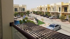 A residential area with modern apartment buildings, a swimming pool, and parked cars. - Romantic Hideaway One Bedroom Villa (Dubai)