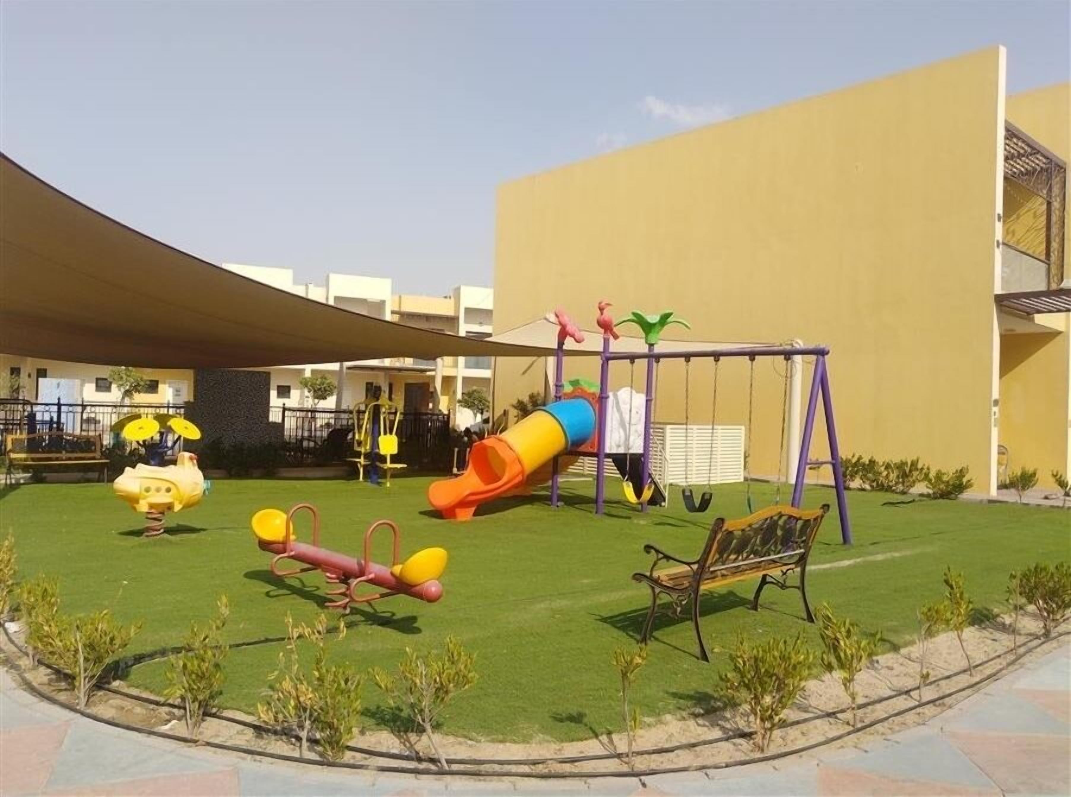 A playground with a slide, swings, and a seesaw.