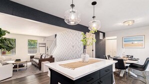 A modern kitchen with a central island, black cabinetry, and pendant lighting.