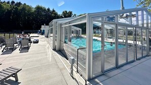 A glass-enclosed pool area with lounge chairs and a clear view of the pool.