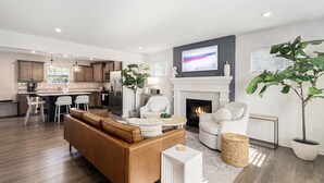 A modern living room with a fireplace, a sofa, a coffee table, and a TV mounted above the fireplace.