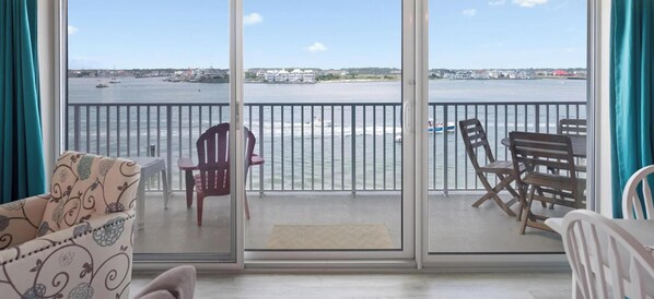 A balcony with a view of the water, a chair, and a table.