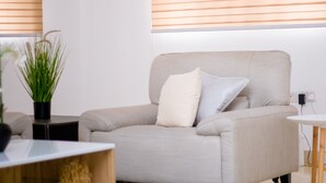 Un soggiorno moderno con un divano beige, un tappeto decorato e un piccolo tavolino con una pianta.