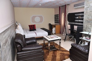 Quarto de hotel com cama, escrivaninha, cadeira e sofá.