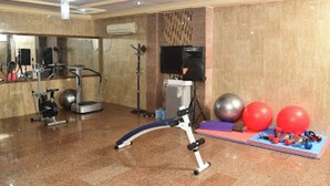 Un gimnasio con equipo de ejercicio, televisión y pelotas de entrenamiento.