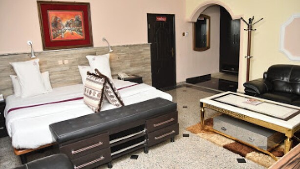 Una habitación de hotel con cama, escritorio, silla, perchero y puerta.