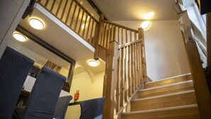 Un escalier avec des rampes et une main courante en bois, menant à l’étage supérieur.