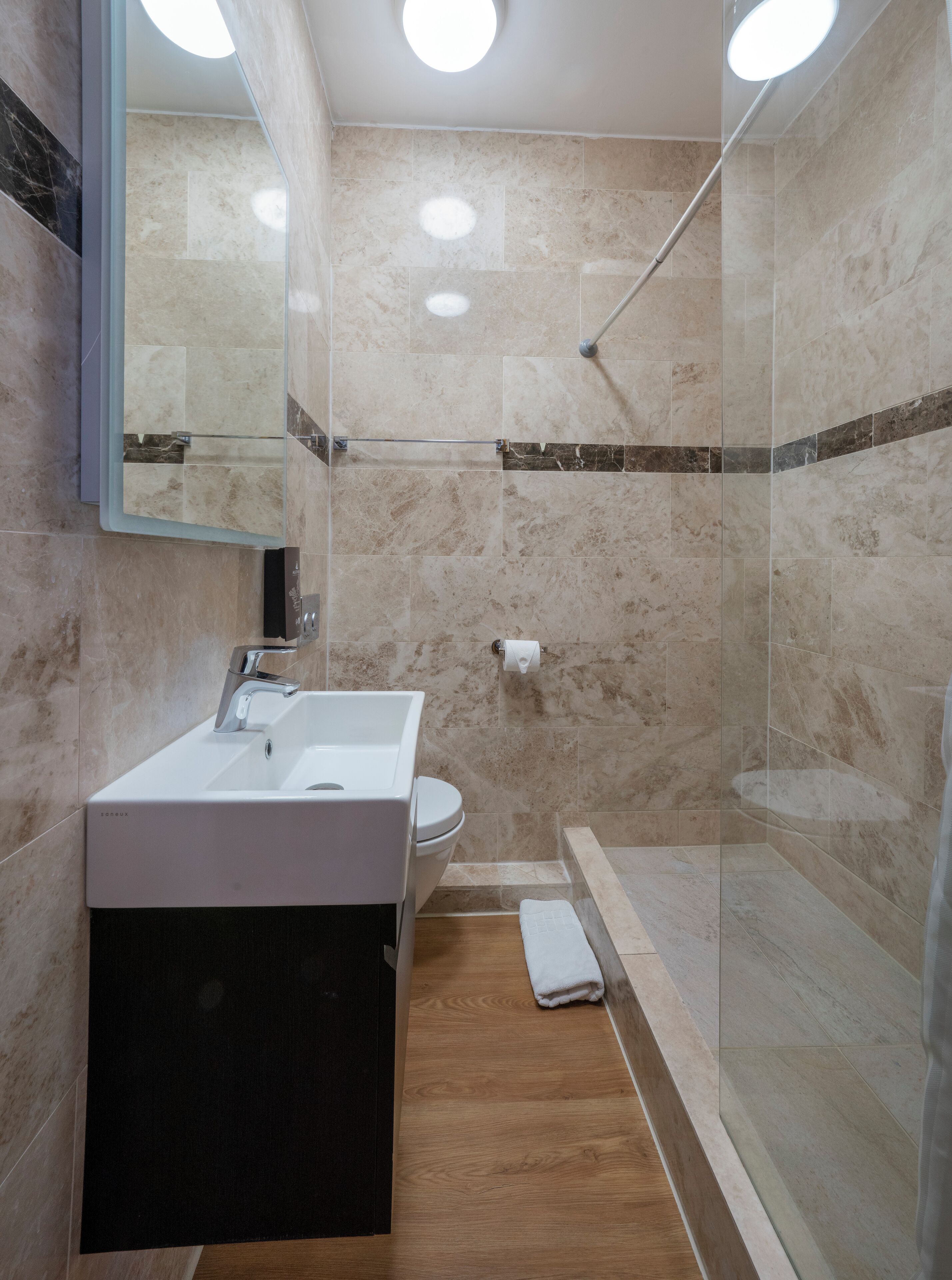Une salle de bain moderne avec une douche à parois de verre, un lavabo blanc et des toilettes.