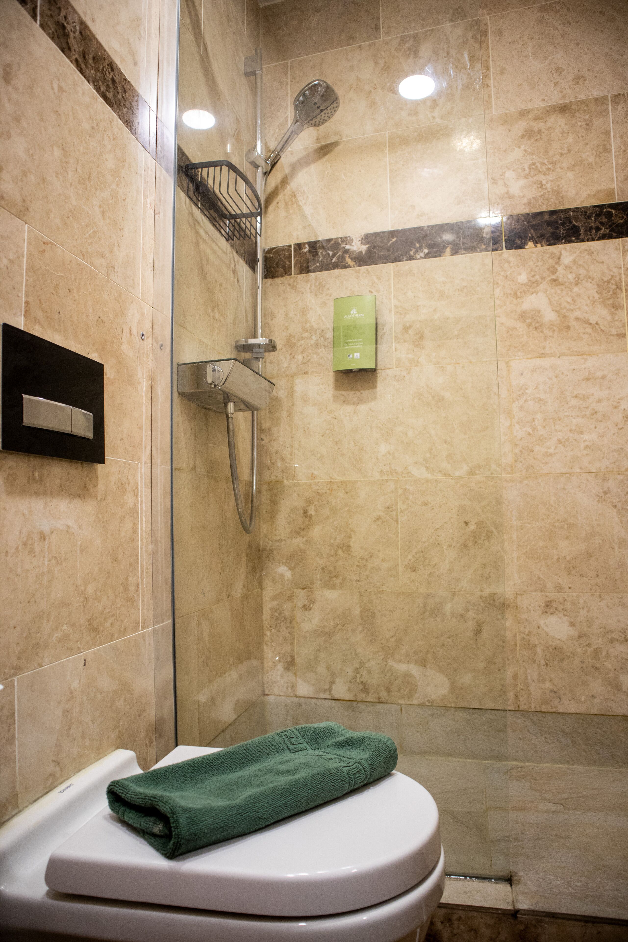 Un baño con ducha, inodoro y una toalla sobre el inodoro.
