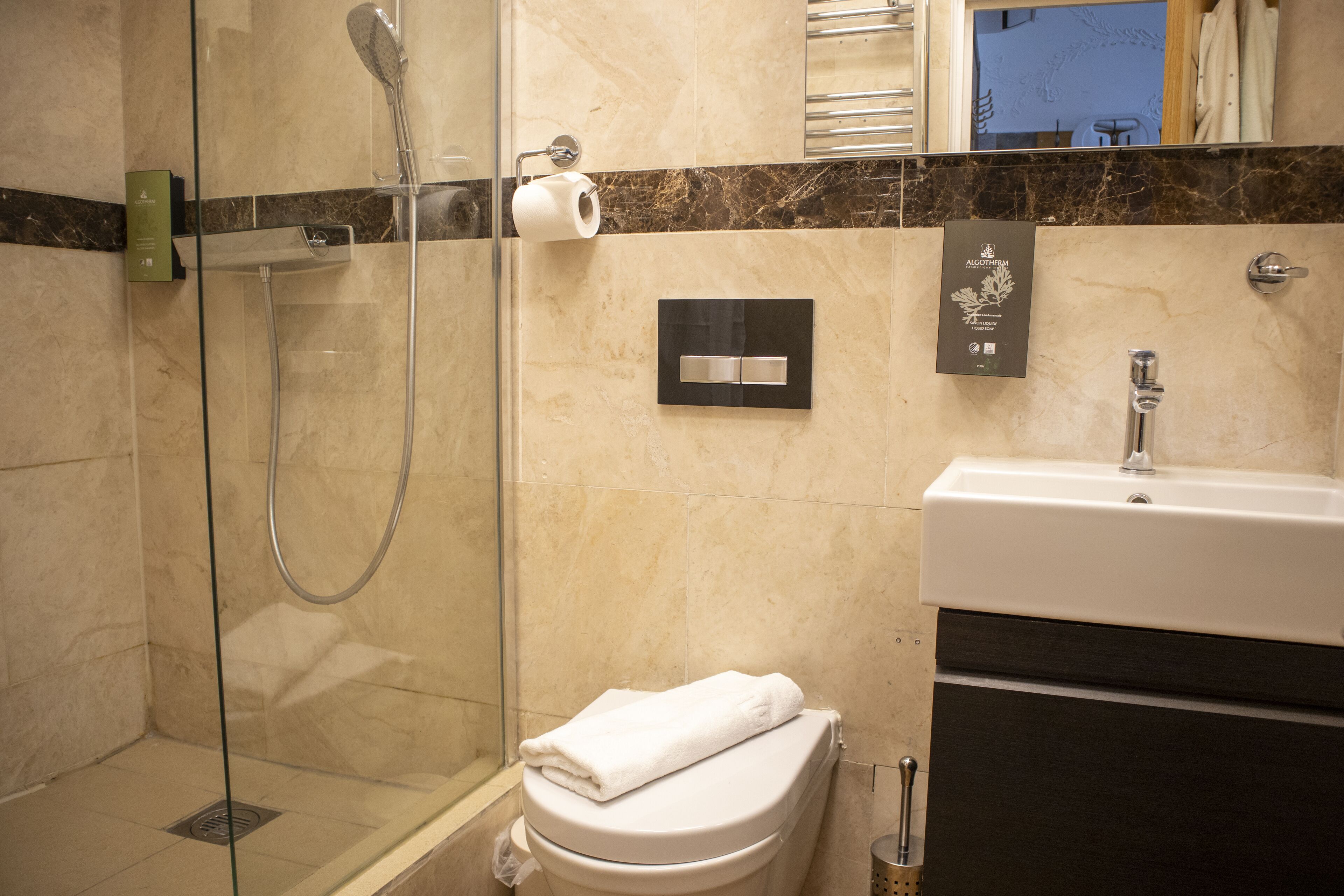 A modern bathroom with a glass-enclosed shower, a toilet, and a sink.