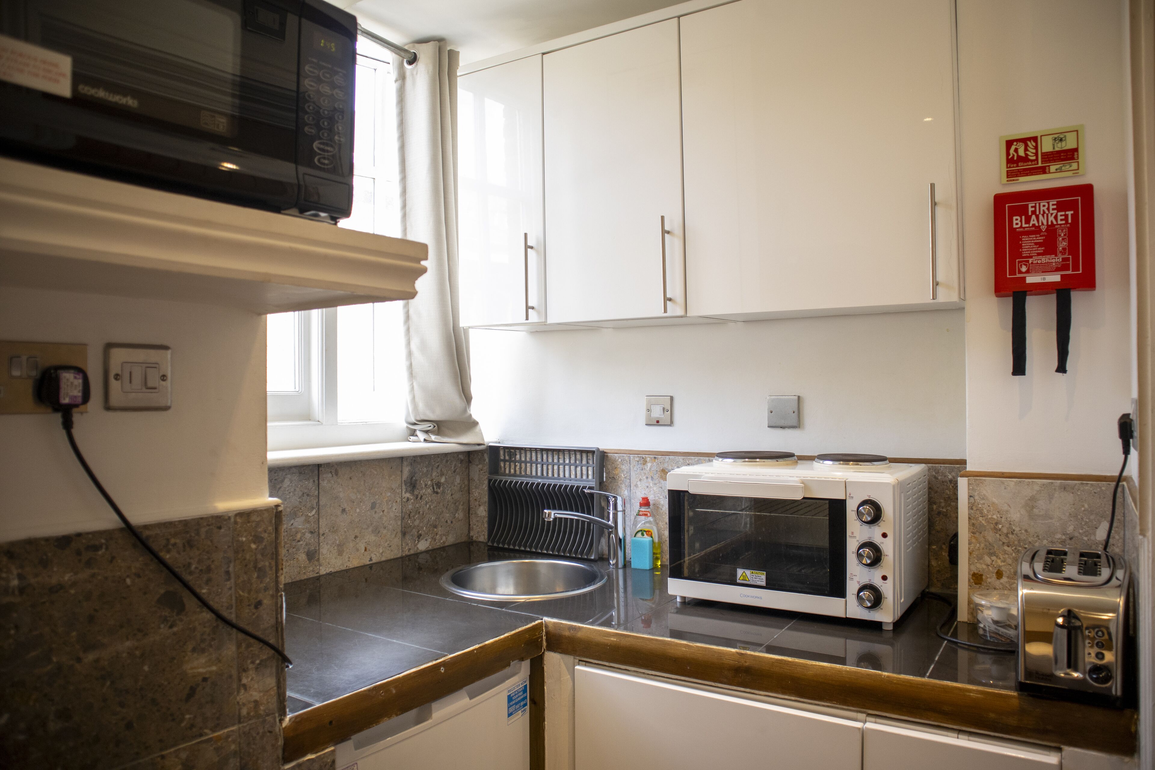 A kitchen with white cabinets, a microwave, a toaster, and a sink.