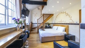 Une chambre d’hôtel comprenant un lit, un bureau avec une chaise, une télévision et un escalier.