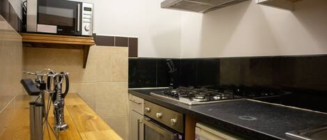 A kitchen with a microwave, stove, oven, and a coffee machine.