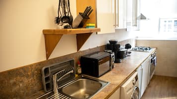 A kitchen with a sink, a toaster, a microwave, and a stove.