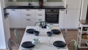 Een eethoek met een witte tafel gedekt voor zes personen, omringd door groene stoelen.
