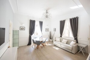 Un salon lumineux avec une table à manger ronde, un canapé et un téléviseur.