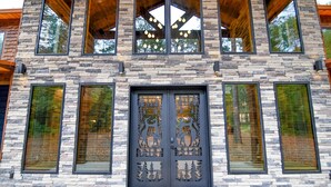 A modern building with a stone facade, large windows, and a decorative door. - Fox Trot Lodge - 6 King Suites - Pickleball Court (Broken Bow)