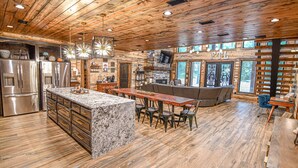 A spacious kitchen with a central island, stainless steel appliances, and a stone countertop. - Fox Trot Lodge - 6 King Suites - Pickleball Court (Broken Bow)