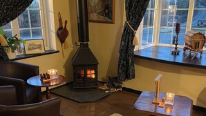 A cozy room with a wood-burning stove, comfortable seating, and a view through a window.