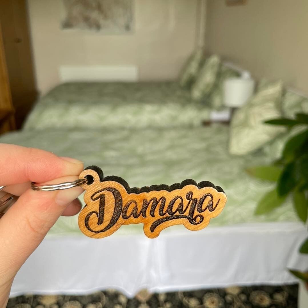 Una mano sosteniendo un llavero con el nombre 'Damara'.