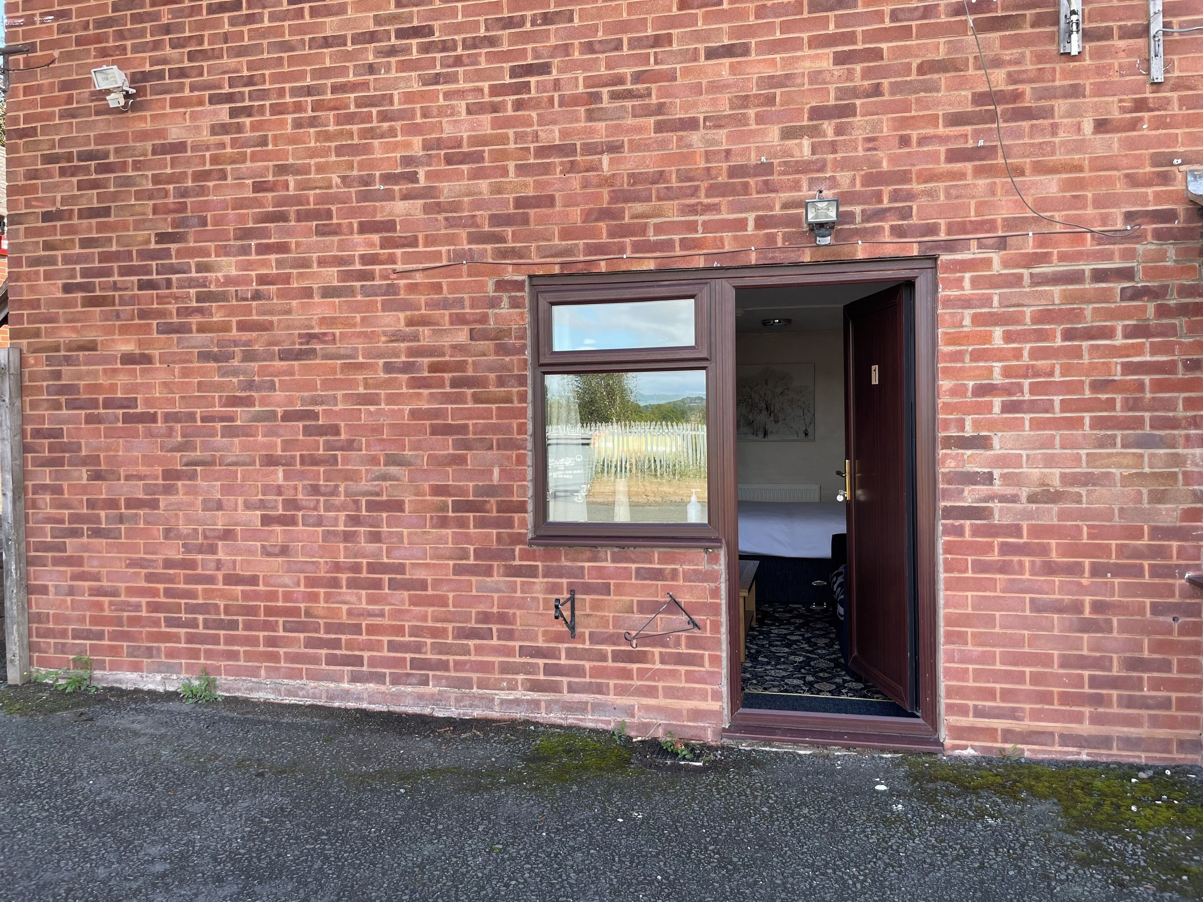 Un edificio de ladrillo con una ventana pequeña y una puerta de acceso.
