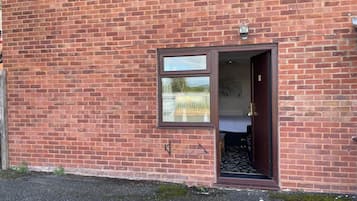 Un edificio de ladrillo con una ventana pequeña y una puerta de acceso.