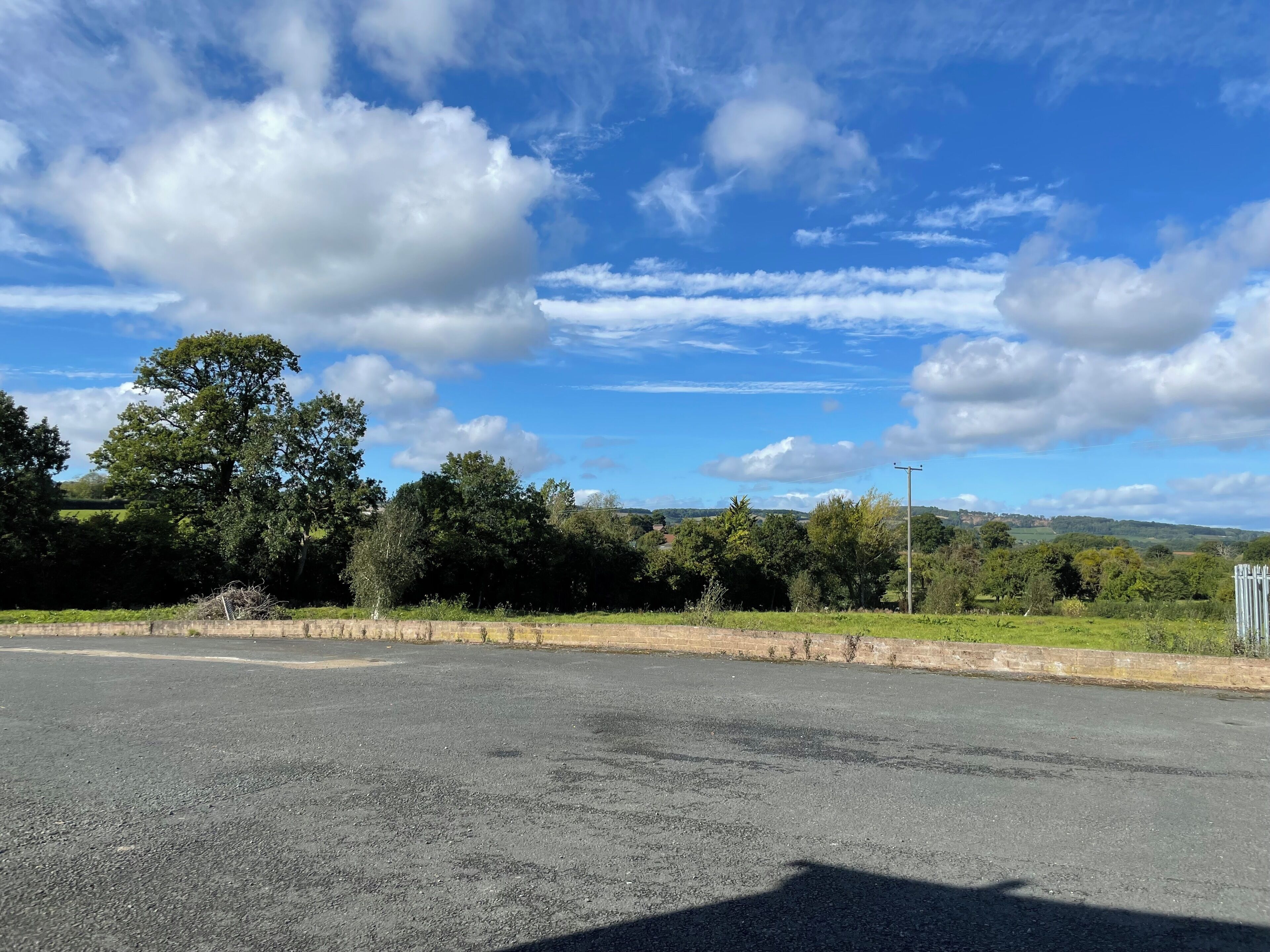 A rural road with a clear sky and scattered clouds.