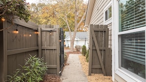 A narrow pathway leading to a gated area with a wooden fence and string lights. - Central Madison Spot Near Work & Attractions (Madison)