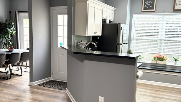 A modern kitchen with grey walls, wooden flooring, and white cabinetry. - Central Madison Spot Near Work & Attractions (Madison)