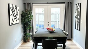 A dining room with a large table, chairs, a potted plant, and artwork on the walls. - Central Madison Spot Near Work & Attractions (Madison)