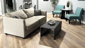 A modern living room with a beige sectional sofa, teal armchairs, a black coffee table, and a ceiling fan. - Central Madison Spot Near Work & Attractions (Madison)