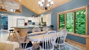 Una cucina moderna con isola centrale, mobili bianchi e un'ampia finestra che si affaccia sul verde.