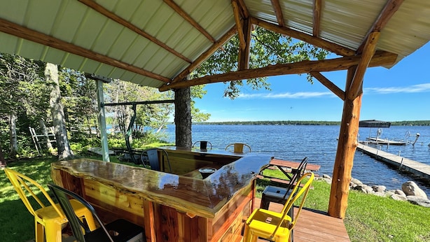 Un pontile in legno con un'area bar, posti a sedere all'aperto e vista su un lago.