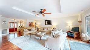 A spacious living room with a ceiling fan, a large window, and a view of the outdoors.