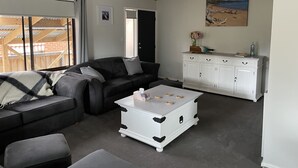Un salon avec un canapé noir, une table basse blanche et un meuble blanc.