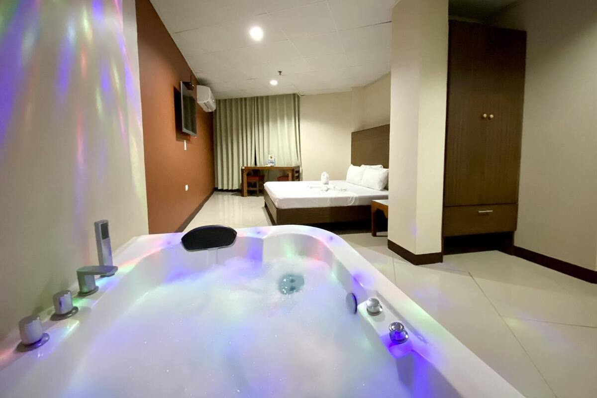 Ein Hotelzimmer mit einer großen Badewanne, einem Bett, einem Schreibtisch und einem Kleiderschrank.