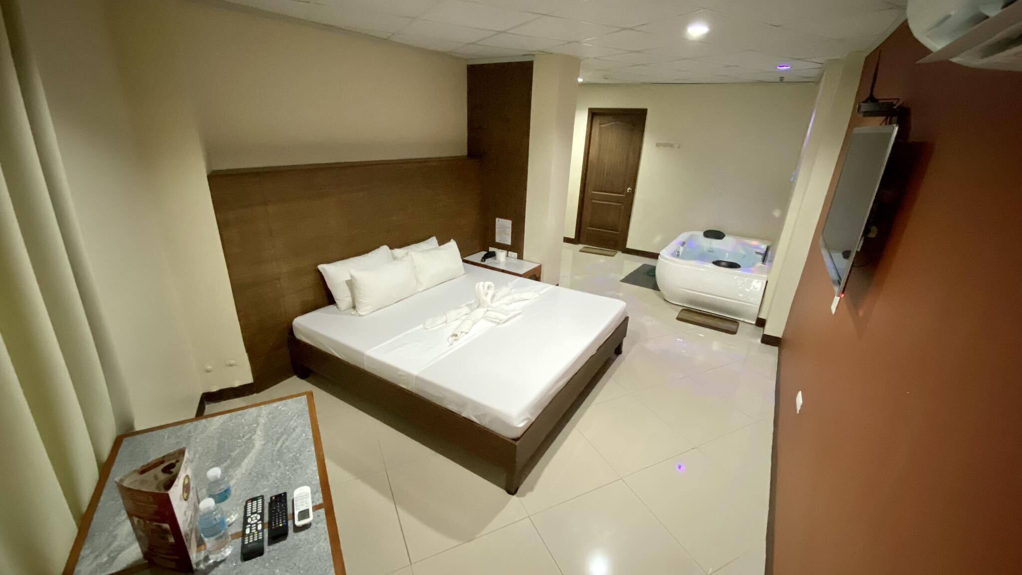 Habitación de hotel con una cama grande, una silla de masaje y una mesita con controles remotos.