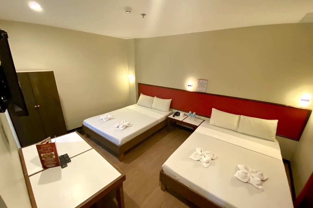 Ein Hotelzimmer mit zwei Einzelbetten, einem kleinen Tisch, einem Schreibtisch und einem Kleiderschrank.