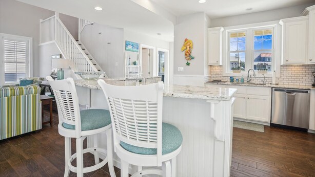 A modern kitchen with white cabinetry, a marble countertop, and a built-in dishwasher. - CH219C- Beautiful Canal front - Kill Devil Hills - Saturday Check In! (Kill Devil Hills)