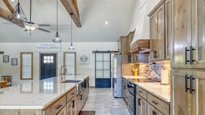 A spacious kitchen with wooden cabinets, a large island, and pendant lighting. - River Ridge @ Frio Premier Rental Homes (Concan)