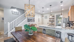 A modern kitchen with a wooden dining table, bar stools, and pendant lighting. - GolfCourseView~6 Person GolfCart~HeatedPool*~Hot tub~FREE GOLF+Pet considered (Miramar Beach)