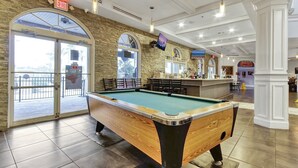 A pool table in a well-lit indoor area with a stone wall and a bar counter in the background. - 4BR Regal Palms | Lazy River, Slide + Arcade (Davenport)