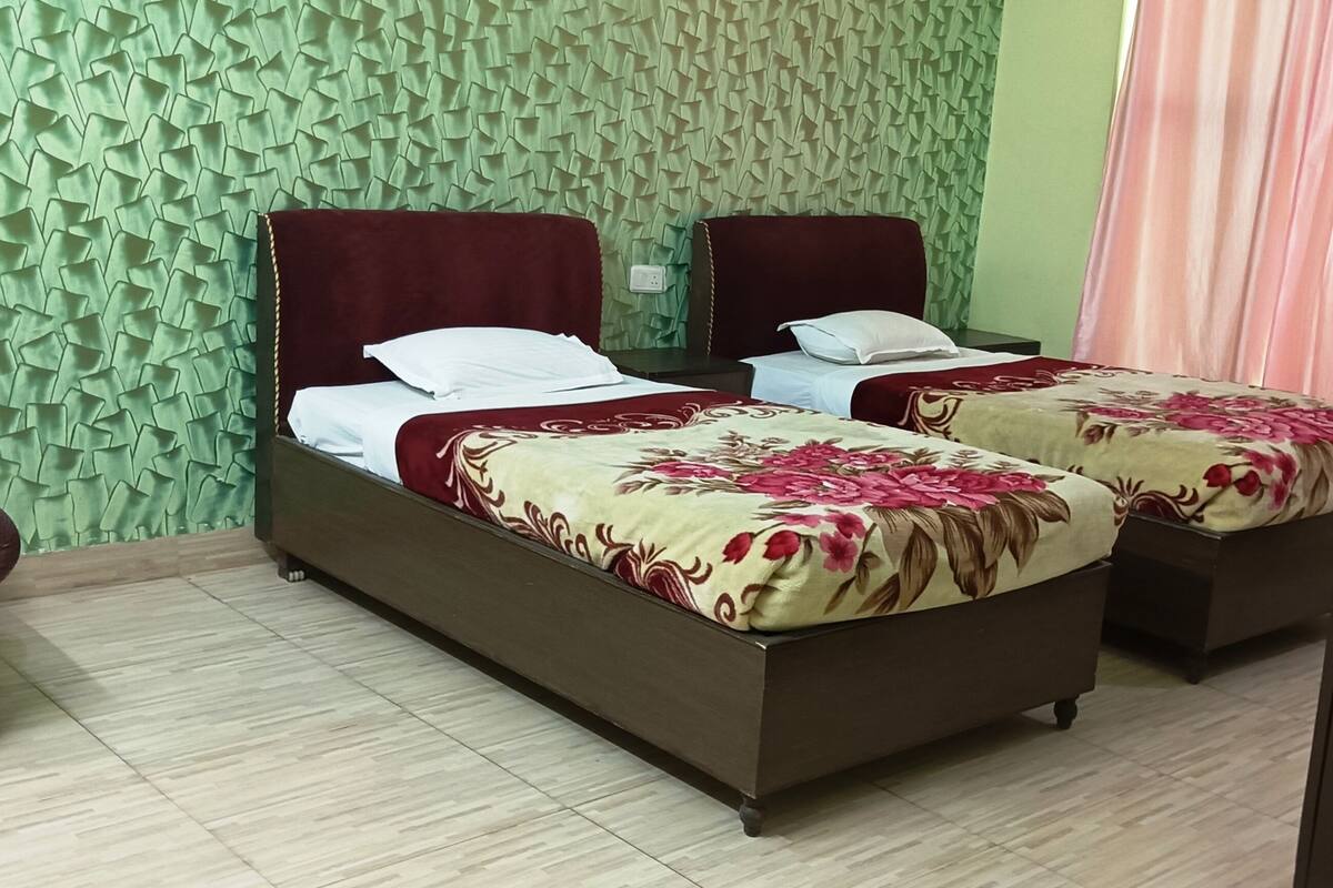 A room with two beds, a sofa, and a patterned wall.