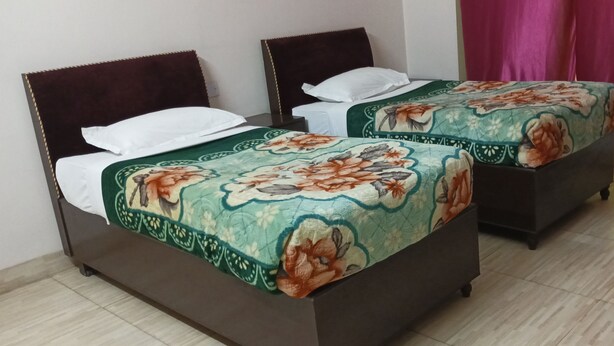 Two single beds with floral bedspreads, a wooden headboard, and a pink curtain.