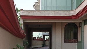 A covered walkway with potted plants, leading to a building with a modern glass facade. - Hotel Galaxy Intercontinental (Gaya)