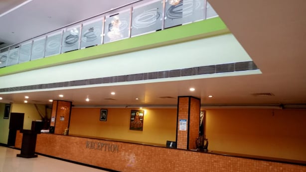 A reception area with a tiled floor, a reception desk, and a wall with framed artwork. - Hotel Galaxy Intercontinental (Gaya)
