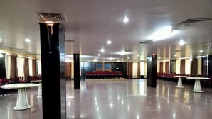 A spacious hall with rows of red chairs and white tables, likely for dining or meetings. - Hotel Galaxy Intercontinental (Gaya)