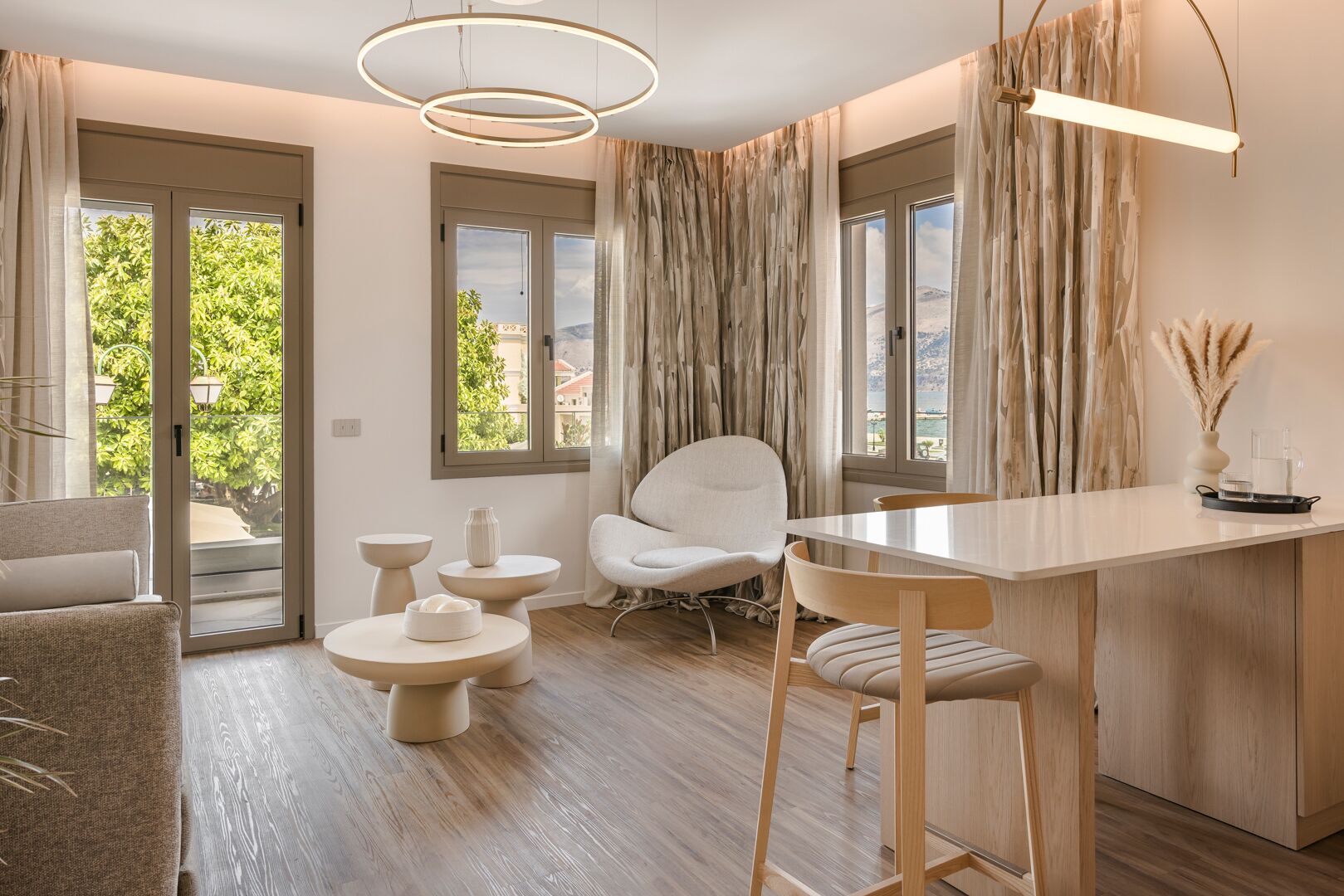 Eine moderne Küche mit Kochinsel, Essbereich mit weißem Stuhl und einer Sitzecke mit Sofa und Beistelltischen.