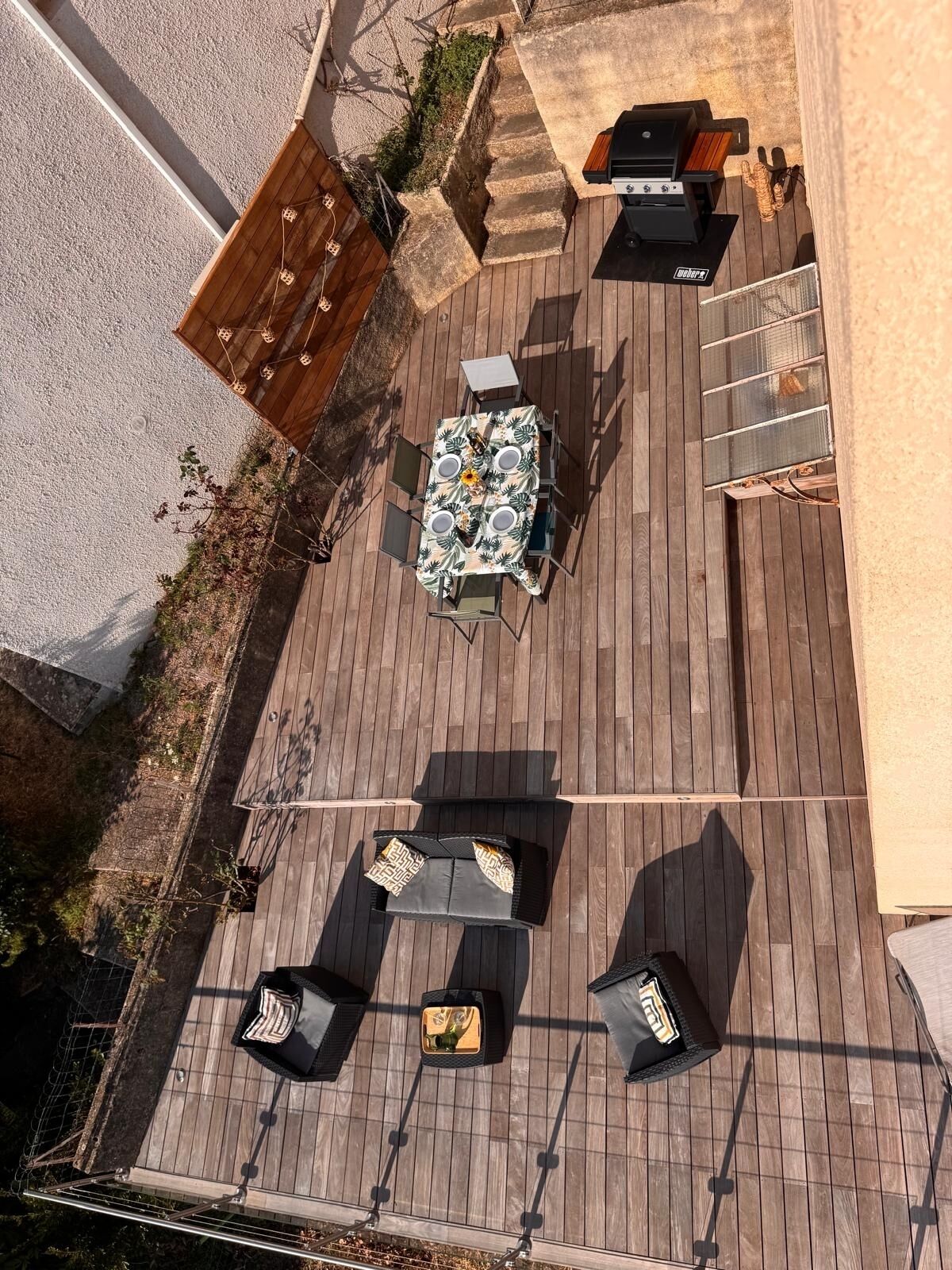 Een terras buiten met een tafel voor vier personen, omringd door vier loungestoelen.