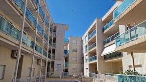 A multi-story residential building with balconies, a swimming pool, and a clear sky. - Apartamento Vacacional con Piscina y Garaje (Torreblanca)